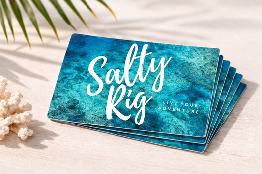 Stack of blue cards with 'Salty Rig' branding on a light surface with coral and palm leaves.