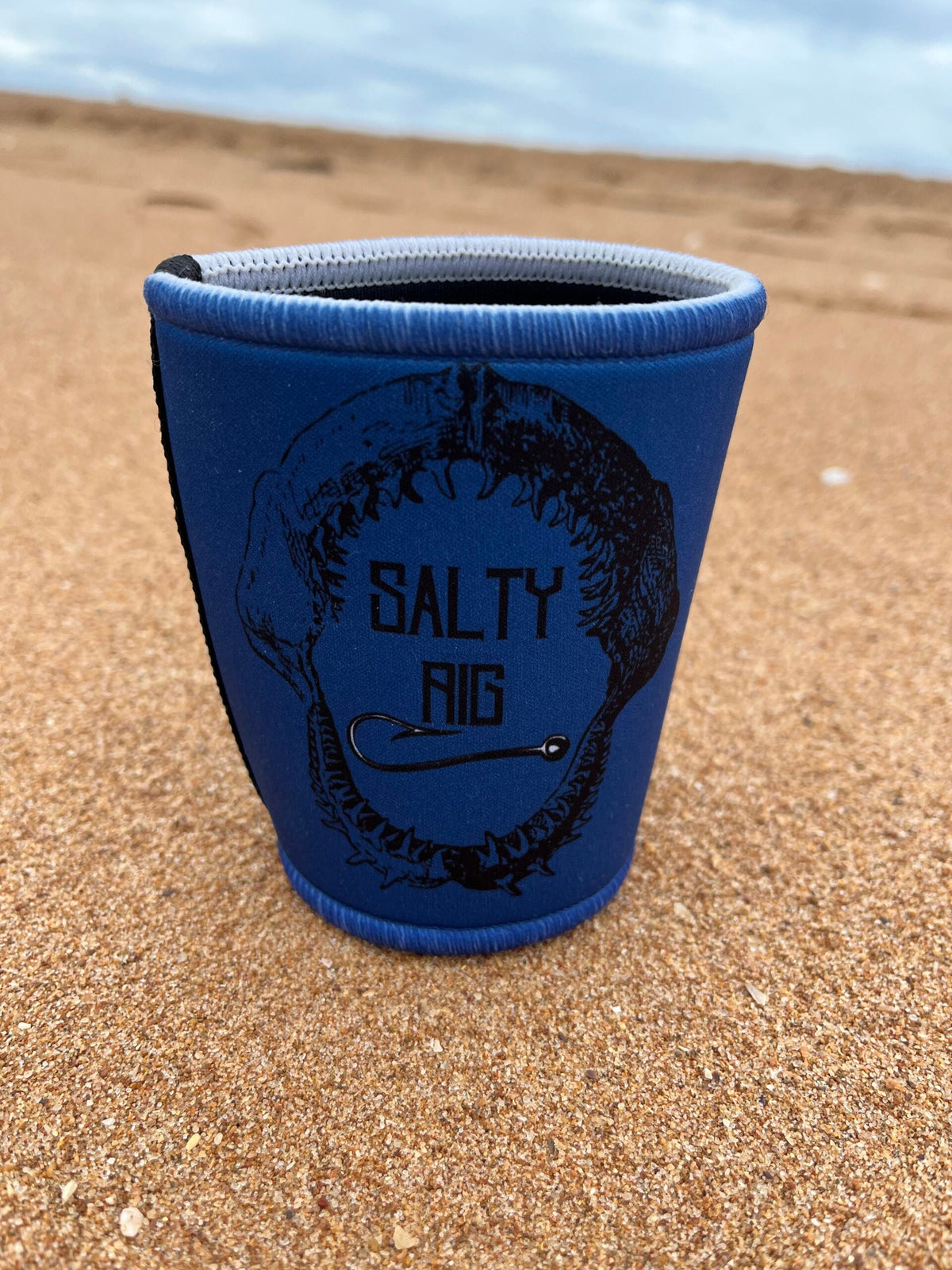 Blue cup holder with 'Salty Rig' branding on a sandy surface